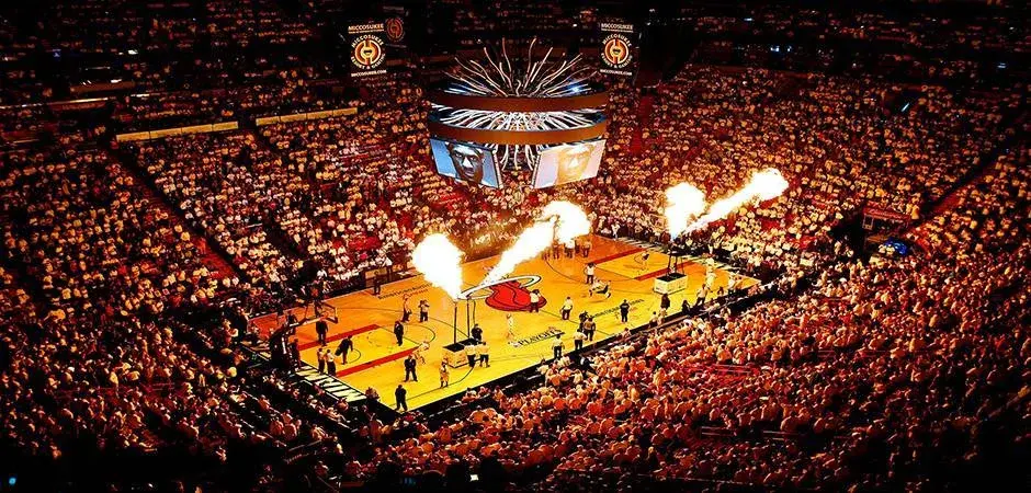 Estadio de basquete lotado de pessoas, com performance pirotecnia na quadra