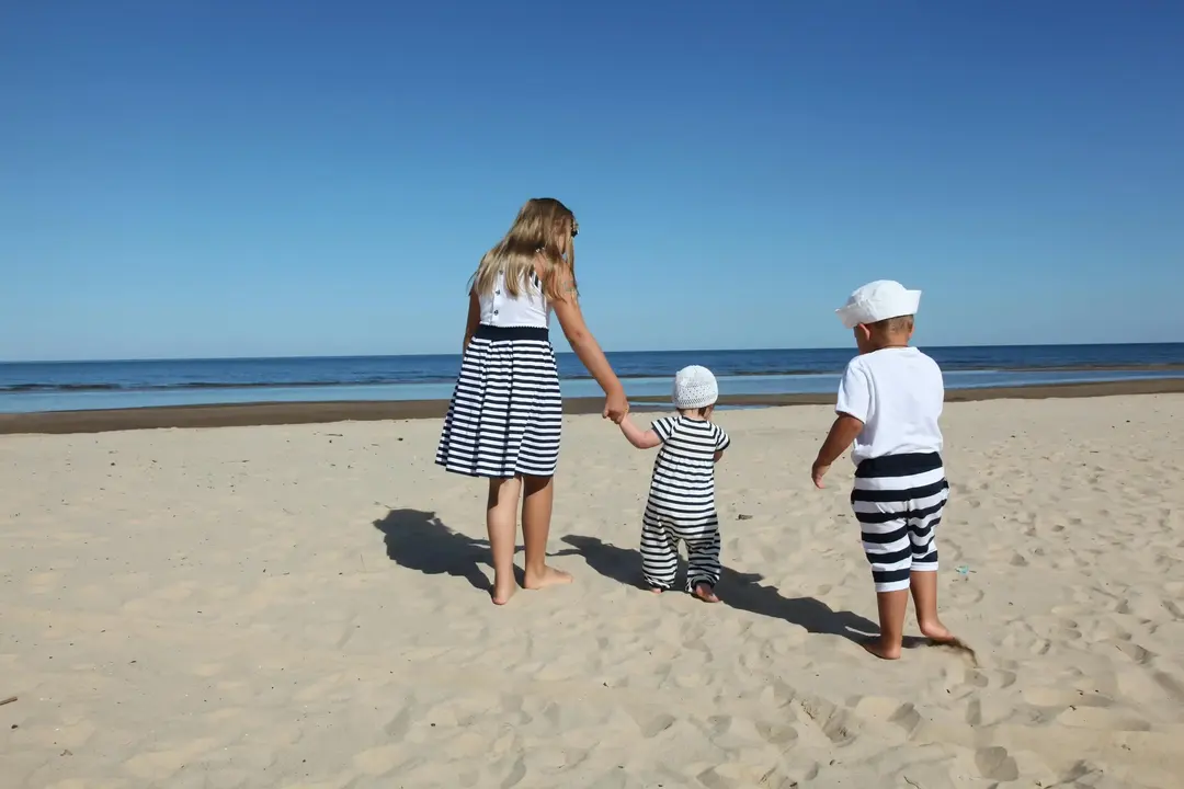 Uma mãe e seus dois filhos e uma praia durante viagem de feriado.