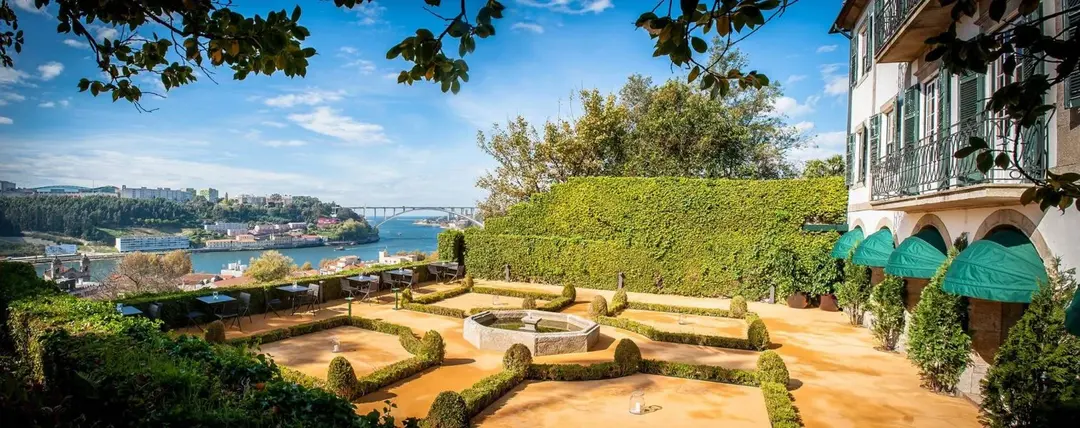 Patio com jardim ao centro, casa ao lado direito, e mar ao lado esquerdo