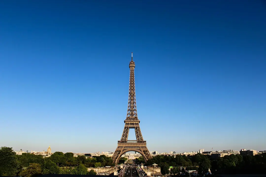 Torre Eiffel em Paris com céu azul claro ao fundo, vista icônica de um dos monumentos mais visitados da Europa.