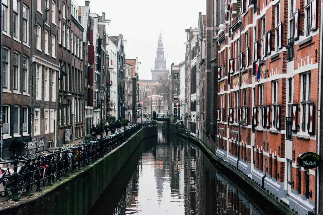 "Canal de Amsterdam com prédios históricos e bicicletas ao longo da margem, destino na Europa para visitar em 2025.