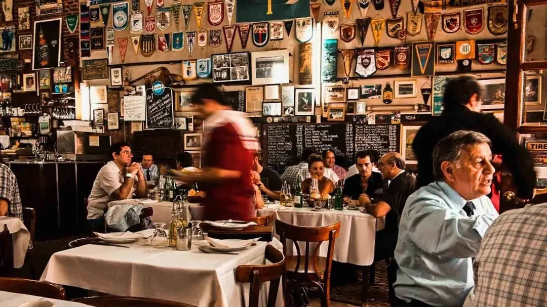 Restaurante com muitas obras de arte na parede, e pessoas comendo nas mesas
