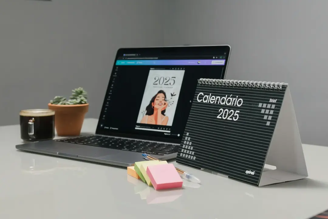 Mesa minimalista com laptop aberto, calendário de 2025, post-its coloridos e uma xícara de café.